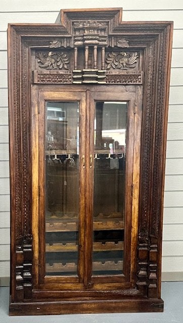 Hand Carved Wine Bar Cabinet: Hand carved wine bar cabinet. Glass front doors. 3 Interior shelves for bottle storage and metal glass rack. Goldwash applied to raised area of carved top. Some wine stains on top shelf. Fronts of gla
