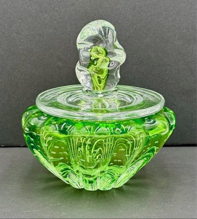 Green Art Glass Lidded Jar: Green art glass lidded jar. Features clear lid with green infused center finial and green jar. Bottom of jar has scratches present. In excellent condition with no chips or cracks. Approximately 7"h x