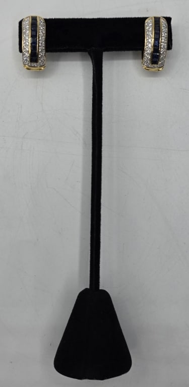 18k Sapphire & Diamond Hoop Earrings 11g TW: Pair of 18k yellow gold sapphire and hoop diamond earrings. Prong set round cut diamonds surrounding a row of square cut sapphires. Filigree backs. Hinged closure. Approximately 1" x .5" and 11.0g TW.