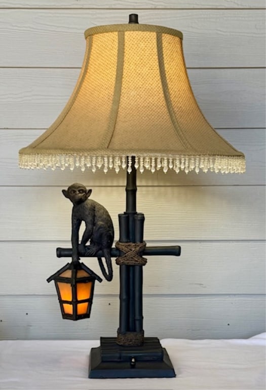 Unique Monkey Lantern Table Lamp: Unique monkey lantern table lamp in the style of Maitland Smith. Made of resin. Features a monkey on a black bamboo style base with a lantern. Fringed cloth shade. Repairs made to base and perch as se