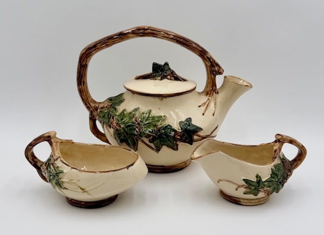 Vintage 1940's McCoy Pottery Ivy Leaf Tea Set: Vintage 1940s McCoy Pottery ivy leaf tea set. The set features a cream colored ceramic body with a brown twig-style handle and a green ivy leaf relief design. Includes 8" teapot, 3.25" creamer, and 3.
