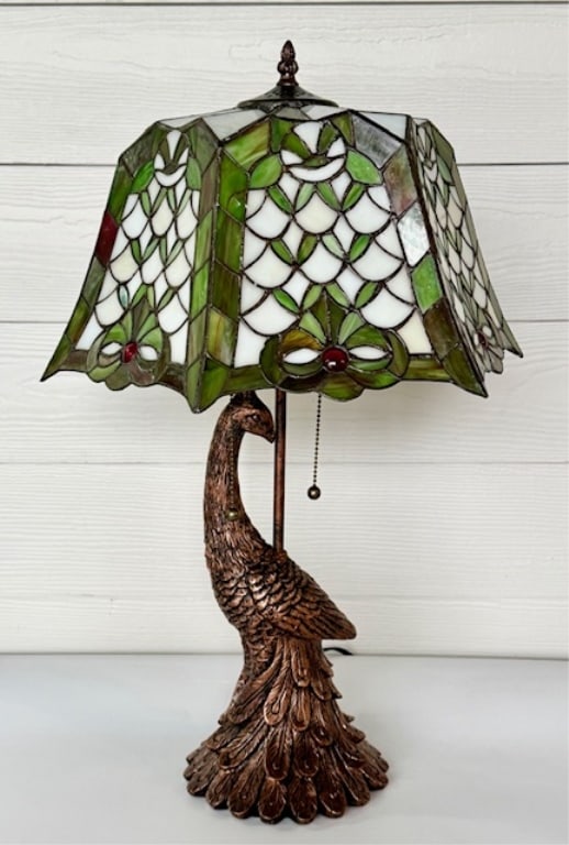 Beautiful Tiffany Style Peacock Table Lamp: Beautiful Tiffany style peacock table lamp. Lamp features composite figural peacock base and leaded style lamp shade. Two bulb. Pull chain on/off. In working condition. Approximately 24.5"h x