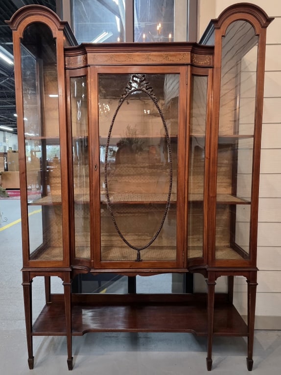 Antique Sheraton Revival Display Cabinet: Antique Sheraton revival mahogany display cabinet . Breakfront design with a central door and curved side sections. Cabinet features satinwood inlays, tapered legs, and a lower open shelf. Fabric line