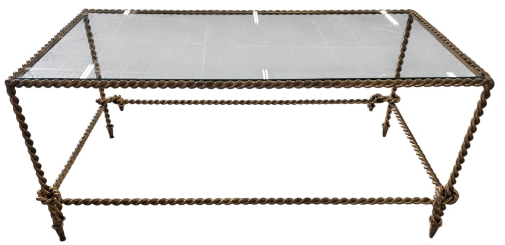 Charlotte & Ivy Gold Twisted Rope Coffee Table: Charlotte & Ivy burnished gold twisted rope coffee table. Features rope twist border, tassel accents, and a glass top. Hand finished iron construction. Approximately 19"h x 42"w x 26"d. Photos