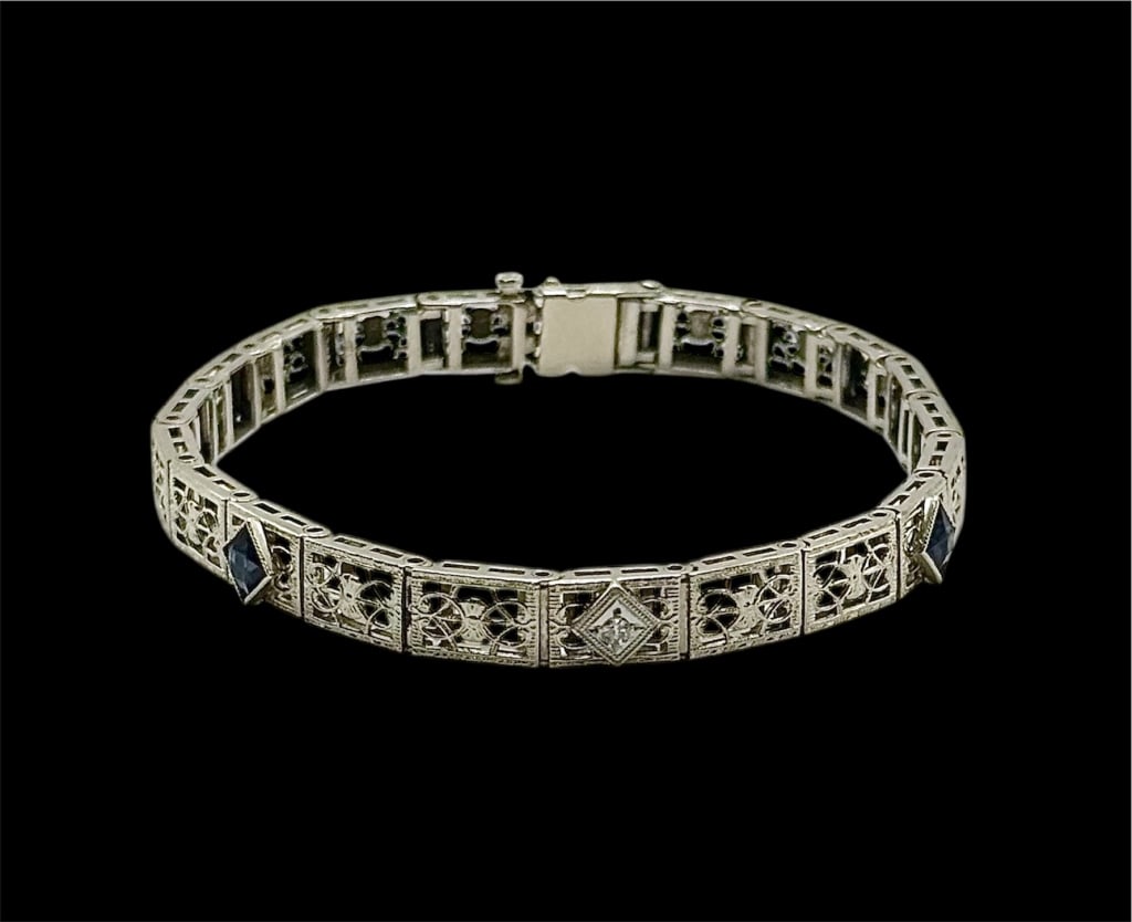 14k Art Deco Filigree Bracelet - 10.93g TW: Beautiful art deco filigree bracelet. White gold featuring a single center diamond and 2 blue glass gems. 10.39g TW. Approx. 7.5"L. Side push button clasp with fold over safety latch. Blue glass gems