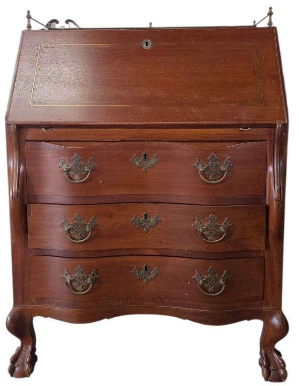 Vintage Slant Front Secretary Desk: Vintage slant front secretary desk. Features a Chippendale style with ball and claw feet, brass gallery, and batwing style drawer pulls. In good condition for age with some scratches and nicks