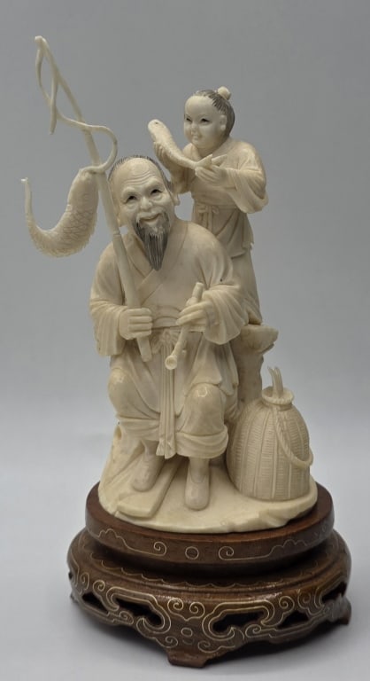 Vintage Carved Asian Okimono Figurine: Vintage carved Asian Okimono figurine. Features a seated fisherman and a young child. Possibly something missing off of fishing pole. Mounted on a wood base. Approximately 6"h. Photos are