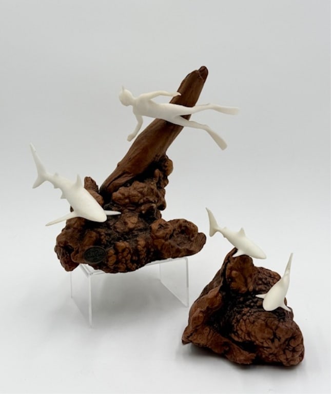 Pair of John Perry Shark Sculptures: Pair of John Perry shark sculptures. Molded from Pellucida resin mounted on polished burlwood bases. Includes 7.5" x 8" diver and shark and 5" x 5" pair of sharks. Chips present on fins as seen in pho