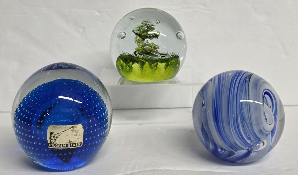Collection of Beautiful Art Glass Paperweights: Collection of beautiful art glass paperweights. Includes Pilgrim Glass blue controlled bubble, 3.5"h, Caithness Glass "Myriad" green abstract paperweight, 3"h, and blue and white swirl, 3"h. Photos ar