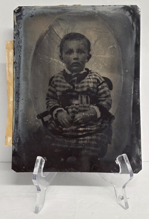 8.5" Antique Tintype Photograph: Antique tintype photograph from the 1800's. Photo depicts a portrait of a young child wearing a checkered outfit. In normal aged condition. Approximately 8.5"h x 6.5"w. Photos are considered part of t
