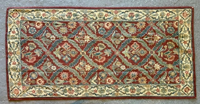 Floral Hand Knotted Rug: Floral hand knotted wool rug. The main field is framed by an elegant, pale cream decorative border filled with continuous undulating vine and flower motifs. In good condition. Approximately 5' x 2'6".