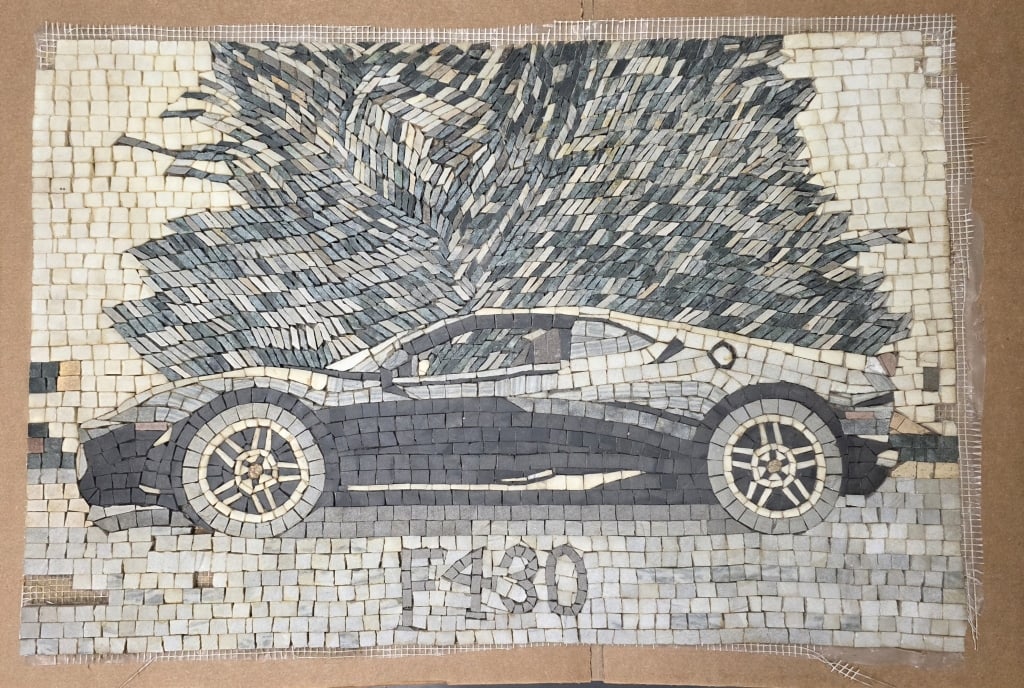 Handmade Tesserae Sports Car Mosaic: Handmade Tesserae artwork constructed from small marble and stone tiles. Features an F-430 sports car. Applied to a soft backing. Missing some pieces. Approximately 17"h x 24"w. Photos are considered 