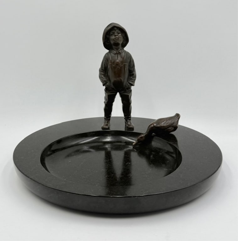 Bronze and Black Marble Figural Desk Tray: Bronze and black marble figural desk tray. The centerpiece features a bronze figurine of a young boy in a hat paired with a duck figure. Solid marble base. Approximately 8"h x 11.75"dia. Photos are co