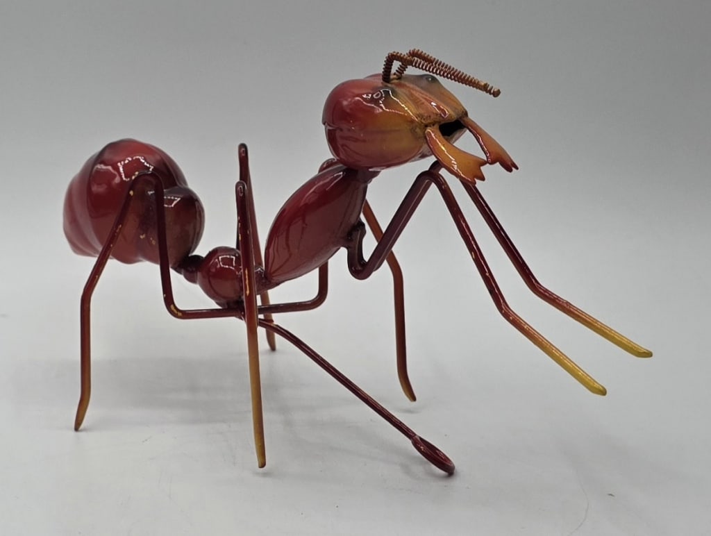 Handcrafted Metal Walking Ant Sculpture: Handcrafted decorative red metal walking ant sculpture. Features a mounting hook on the underside for hanging. Approximately 3.5"h x 6.5"w. Photos are considered part of the condition and description.