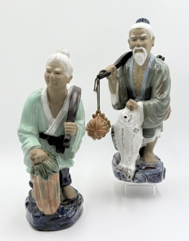 Pair of Large Chinese Shiwan Mudmen Figures: Pair of large Chinese Shiwan Mudmen figures. Includes 14.5" male figure holding a large white carp while carrying a shoulder yoke with dangling baskets, symbolizing a bountiful catch, and 14" female f