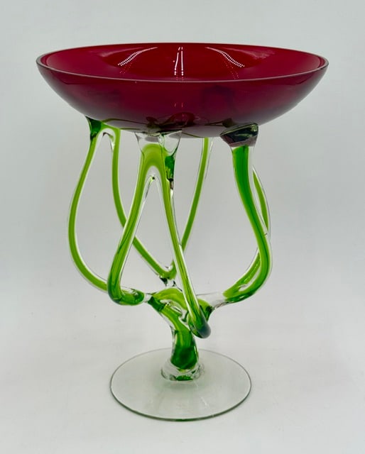 Stunning Art Glass Jellyfish Pedestal Bowl: Stunning art glass jellyfish pedestal bowl. Hand blown in Poland. Features a vibrant, deep ruby red cased bowl perched atop emerald-green wrapped ribbons. In excellent condition with no chips or crack