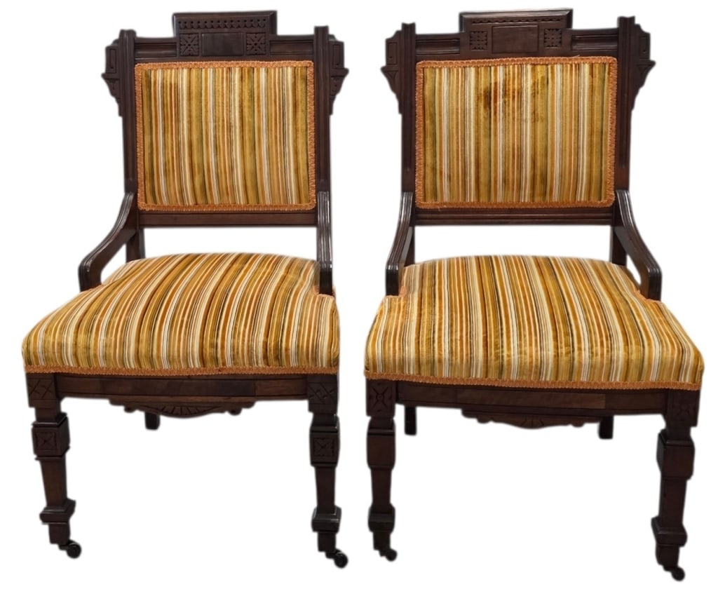 Pair of Vintage Eastlake Style Parlor Chairs: Pair of vintage Victorian Eastlake style parlor arm chairs. Chairs feature striped gold upholstery and detailed carvings. Wood castors on front of chairs. In good condition for age with some staining 