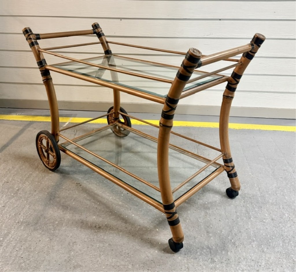 2 Tier Faux Bamboo & Glass Rolling Tea Cart: 2 Tier rolling tea cart. Cart features a metal construction painted to mimic bamboo and two levels with inset glass shelves. Approximately 34.5"h x 49"w x 22"d. Photos are considered part of the condi