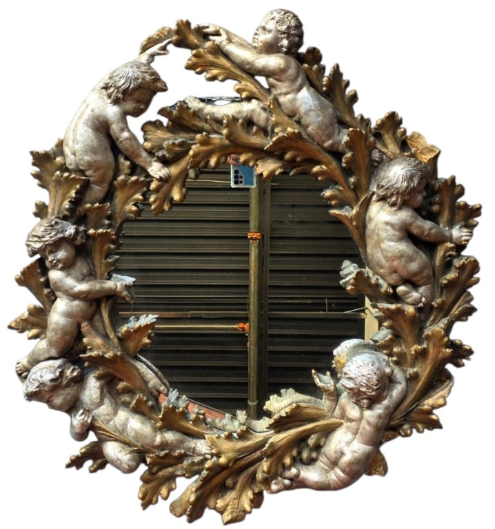Antique Ornate Gilded Cherub Wall Mirror: 19th century Italian Rococo style ornate gilt wreath wall mirror. Mirror adorned with six carved cherubs and flowing acanthus leaves. Constructed from a carved composition over a wood backing. Very he