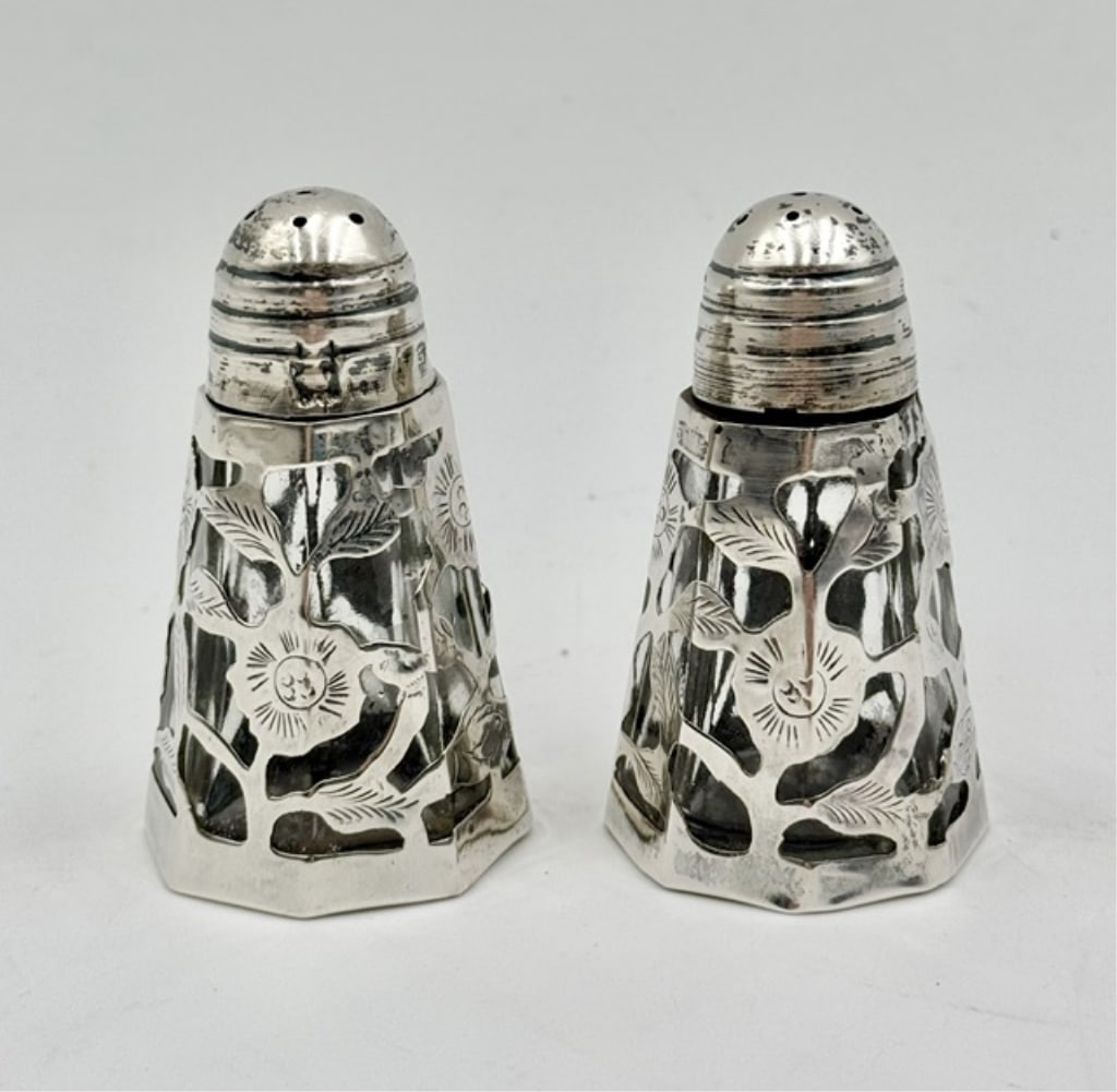 Vtg. Mexican Sterling Silver Overlay S&P Shakers: Vintage Mexican sterling silver over salt and pepper shakers. Shakers feature an intricate pierced floral design encased in .925 sterling silver over an internal glass body. Some dents and tarnish pre