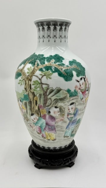 Chinese Famille Rose Porcelain Vase: Chinese famille rose porcelain vase. Features a hand painted scene of children playing in a landscape. Signed/Stamped on bottom. On removable wood stand. Excellent condition with no chips or cracks.