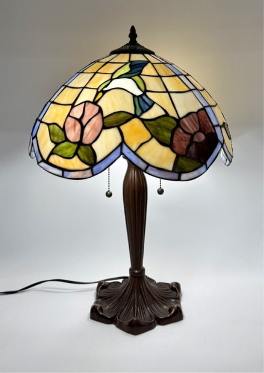 Vtg. Hummingbird Tiffany Style Stained Glass Lamp: Vintage Tiffany style stained glass table lamp. Features a handcrafted dome lampshade with a hummingbird and floral pattern. Fluted metal base in an antique bronzed finish. Dual lite with pull chain o
