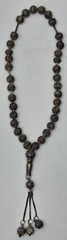 Vintage 80% Silver Tasbih Prayer Beads: Vintage 80% silver Tasbih prayer bead strand. Features 80% silver filigree beads and a central elongated master bead, which connects to a chain tassel. Tassel decorated with smaller dangling charms at
