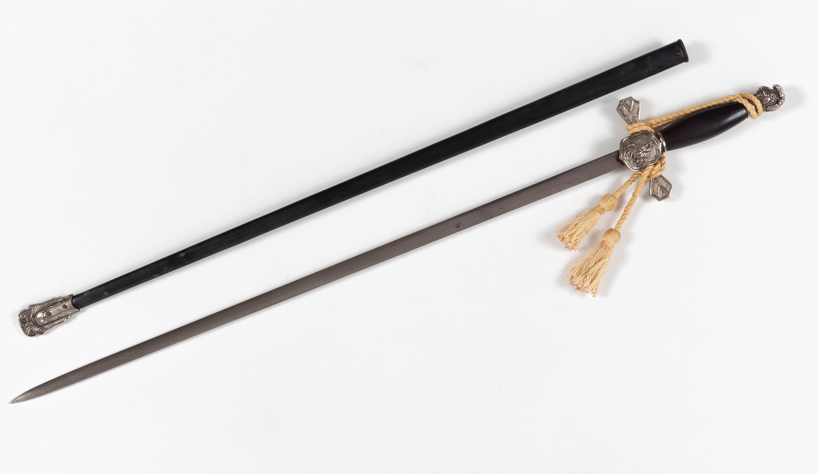 KU KLUX KLAN DRESS SWORD: KU KLUX KLAN dress sword with scabbard. Rounded smooth black grip, the silvered pommel is in the shape of a knight's helmet, the crossguard is decorated with a shield with a mounted hooded clansman ca
