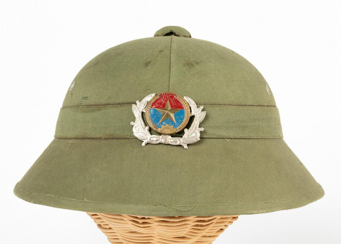VIETNAM NORTH VIETNAMESE PITH HELMET: VIETNAM NORTH VIETNAMESE PITH HELMET North Vietnamese pith helmet with a plastic chin strap, liner complete, and green cloth cover. This helmet features the North Vietnamese badge, featuring a five-po