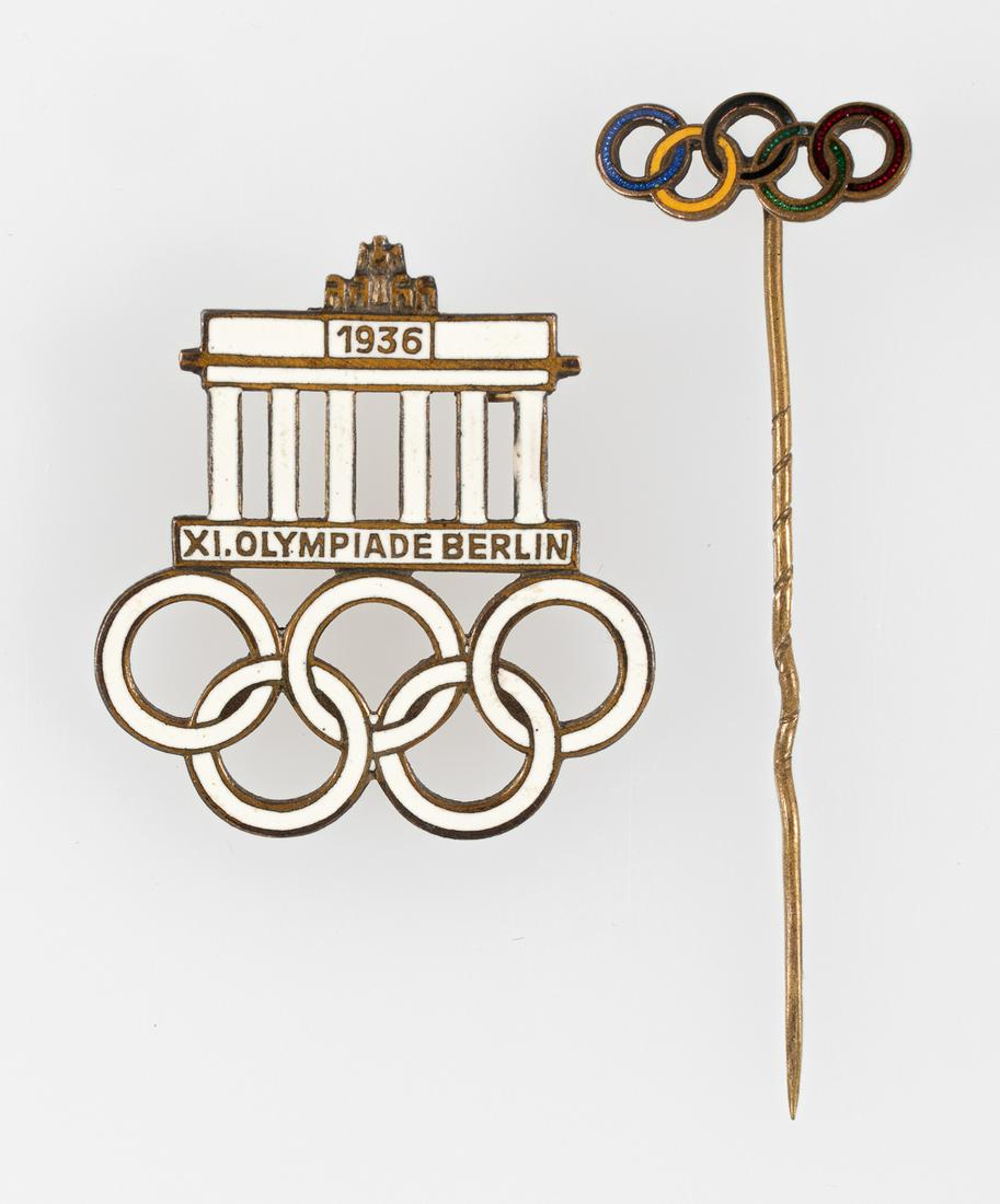 1936 OLYMPIC GAMES PINS (2): 1936 OLYMPIC GAMES PINS (2)1936 official Olympic Games pins, one in white enamel featuring the Brandenburg Gate and Olympic rings commemorating the 1936 Olympic Games in Berlin. Makers mark on reverse