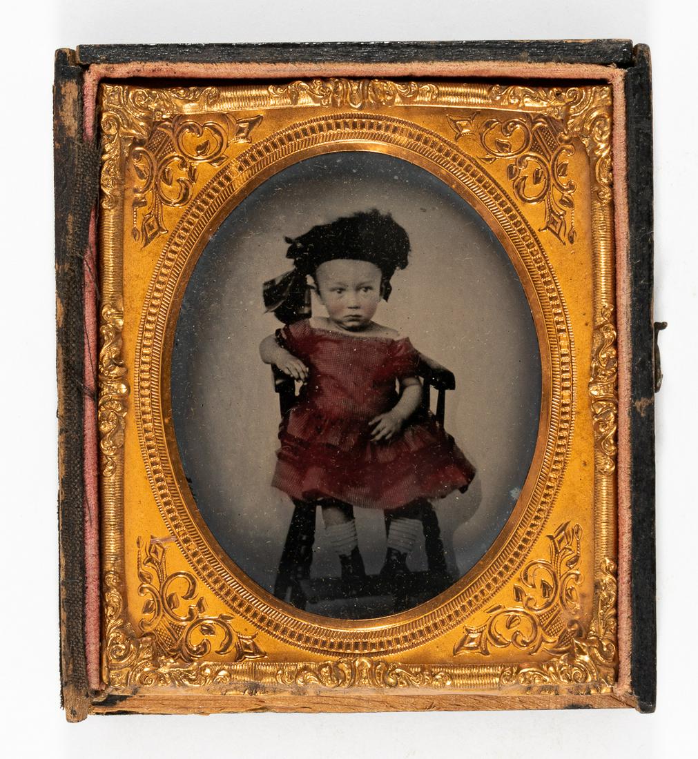 AMBROTYPE OF A LITLLE GIRL HANDTINTED: AMBROTYPE OF A LITLLE GIRL HANDTINTED Sixth plate ambrotype of a little girl, seated on a chair. Her dress is hand tinted in red. Cover and bottom edge of the case missing, else fine.