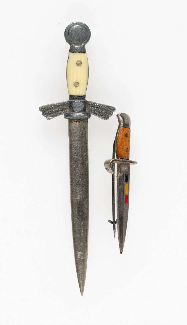 LUFTWAFFE SWORD & DAGGER TINNIES (2): Miniature Luftwaffe sword tinnie and a miniature dagger with a pin back. Two pieces.