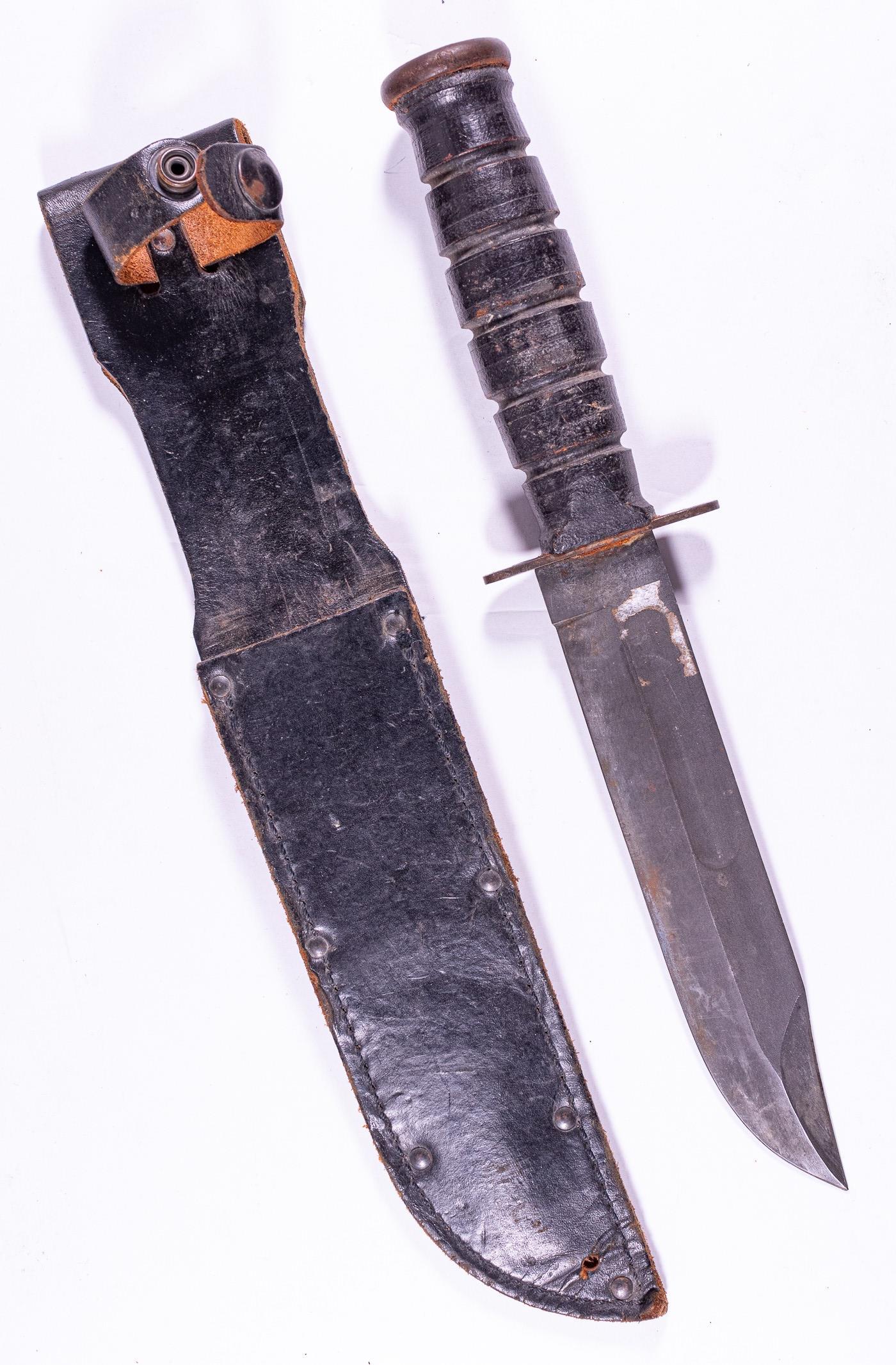 US CAMILLUS FIGHTING KNIFE WITH SCABBARD: Knife with maker's mark, 'Camillus New York, U.S.A.' with leather scabbard. Sharpened knife has minor rust at cross guard. Leather scabbard is supple with minor abrasions. Overall length is 12 inches.