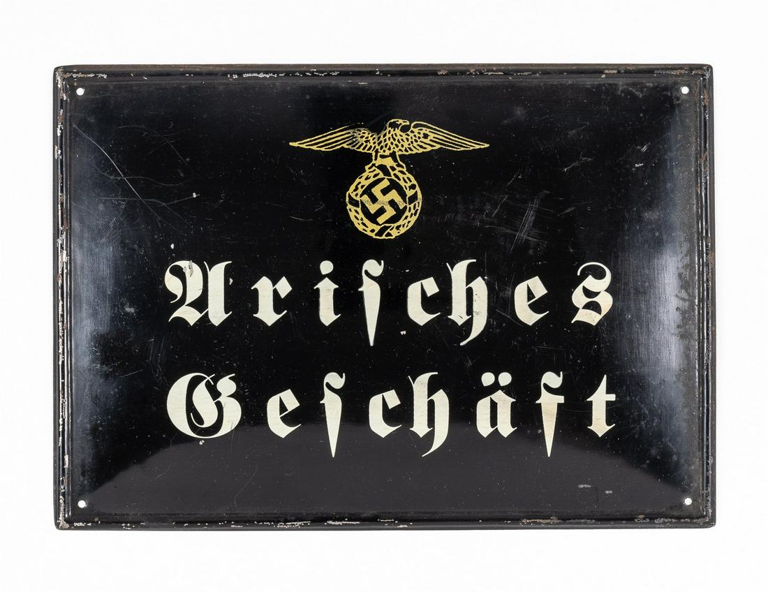 GERMAN ARYAN BUSINESS PLAQUE: Black enameled metal sign with bold white text reading 'Arisches Geschaft' ('Aryan Business'), beneath a gold Nazi eagle clutching an oakleaf wreath with mobile swastika. Mounting holes in each corner