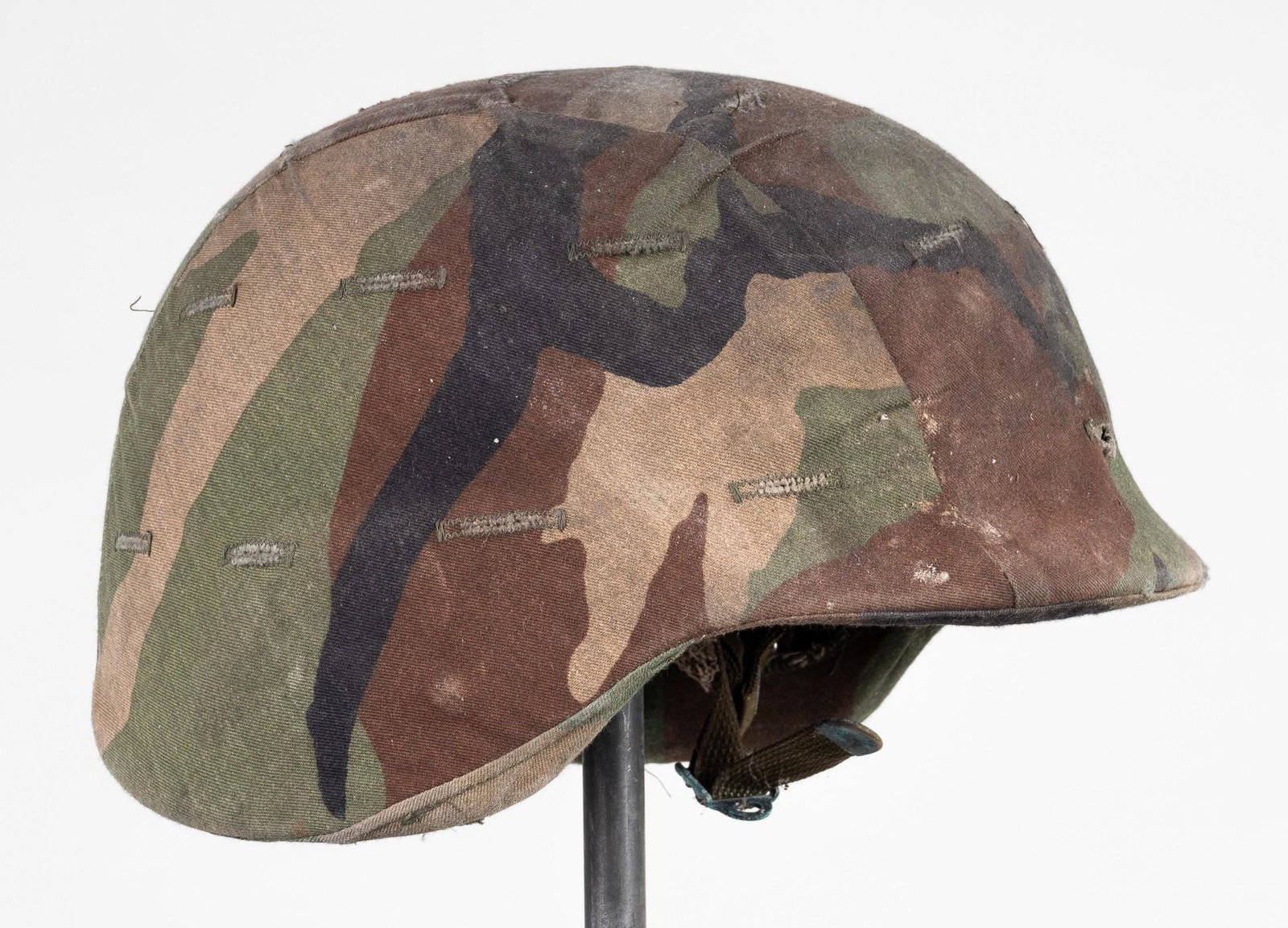MODERN US ARMY KEVLAR HELMET: Kevlar army helmet for the US military covered in camouflage fabric with intact leather liner and chin strap. Markings on the inside, 'Helmet Ground Troops Parachutist - Contract # DLA 160-83-C-4223 -