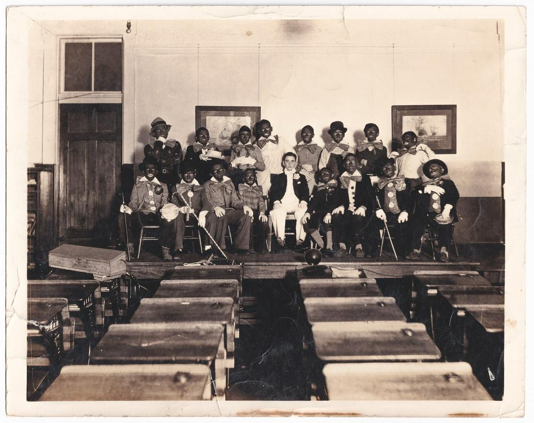 1920'S BLACK FACE PHOTO: Black- and white photograph from the 1920s showing sixteen children in blackface in a school play. Inscription on verso, 'To my fellow minstrel Marion Tucker From Bob Holder (Bones)'. 8 x 10 inches. 1
