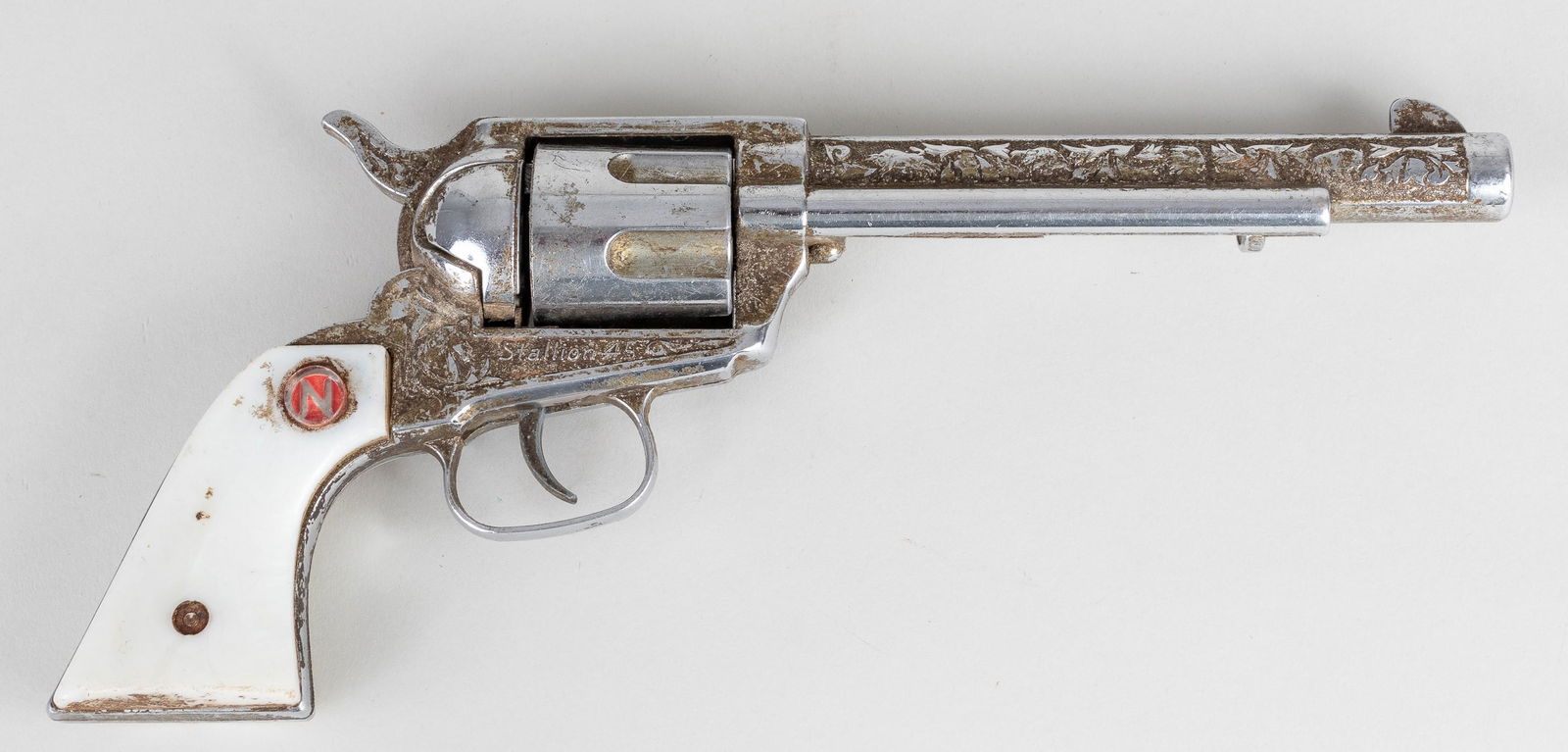 NICHOLS STALLION 45 CAP GUN: Vintage toy cap gun 'Stallion 45' made by Nichols, from the 1950s, with white grip and die-cast filigree barrel, hammer, and frame. Approx. 12 inches in length. The cylinder does not spin and the lot