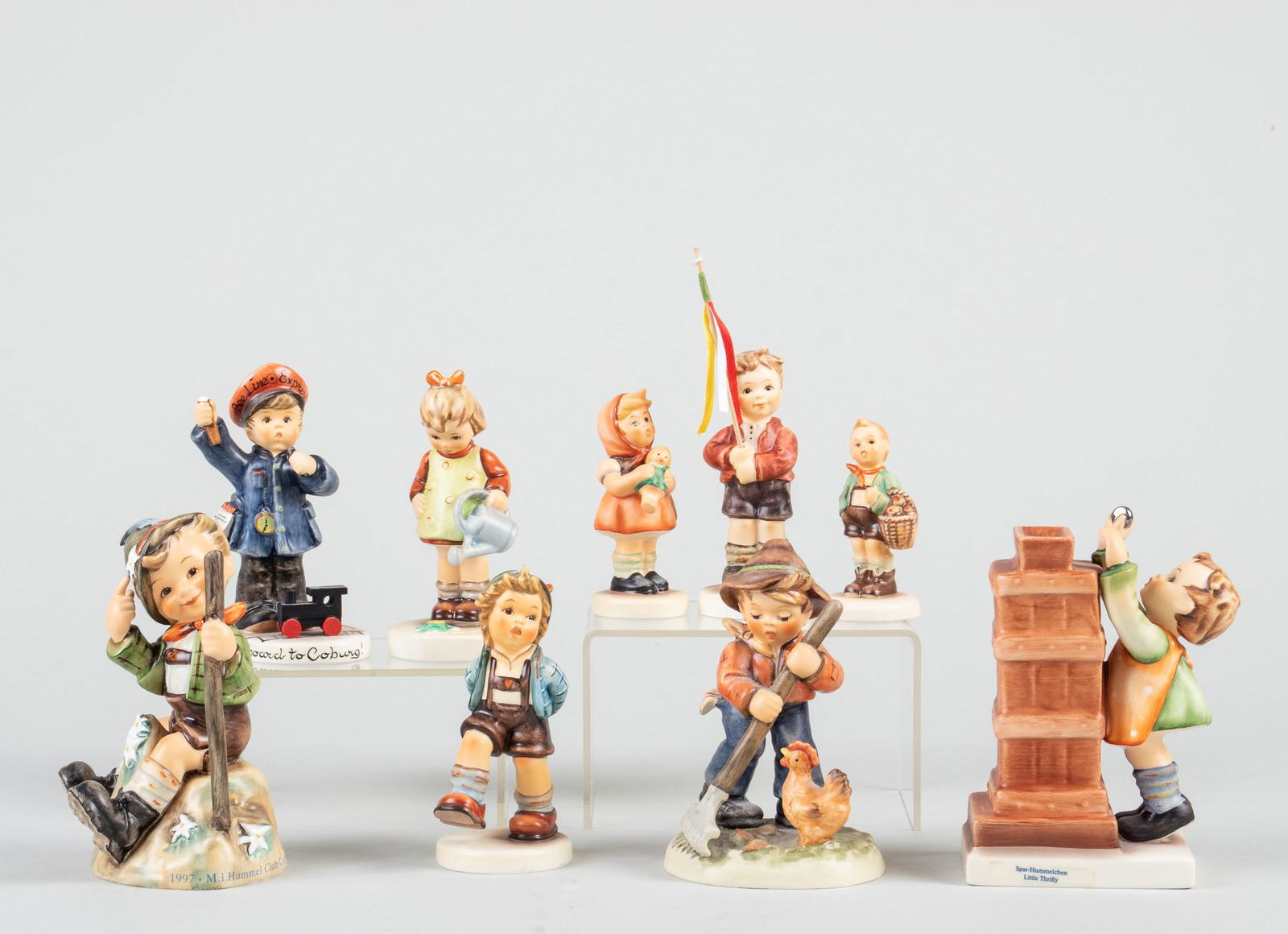 9 GOEBEL HUMMEL FIGURINES: Lot of nine German Hummels, including 'Mountaineer #1203', 'Little Farm Hand #1497', 'All Abroad #2044', 'Alpine Dancer #1703', 'Spring Gifts #2273', 'Village Boy', 'Girl with Doll #821', 'Little Thri