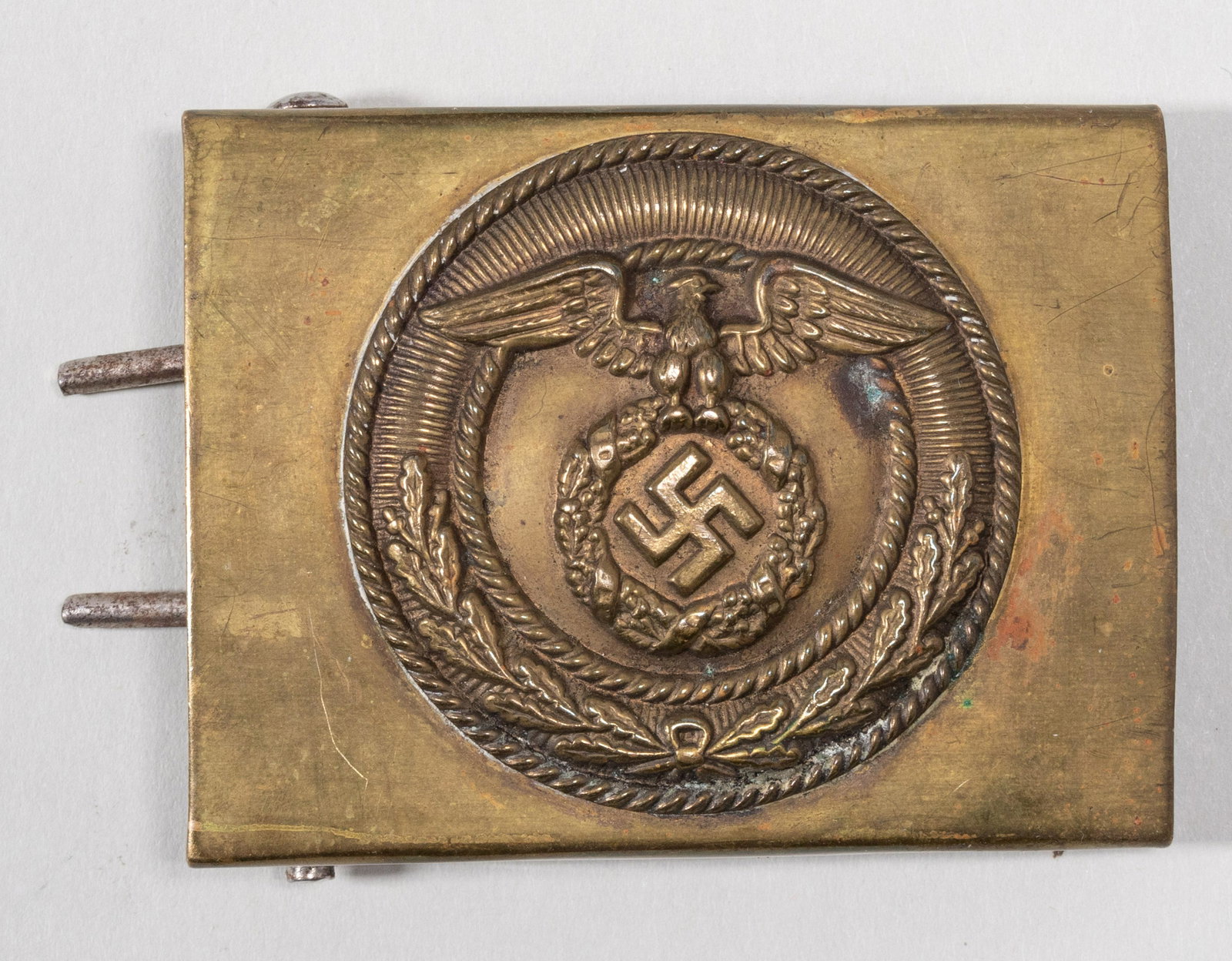 GERMAN SA BELT BUCKLE: Brass-colored belt buckle with Nazi eagle and mobile swastika relief, approx. 2.5 x 2 inches. Minor tarnishing and scuffing.