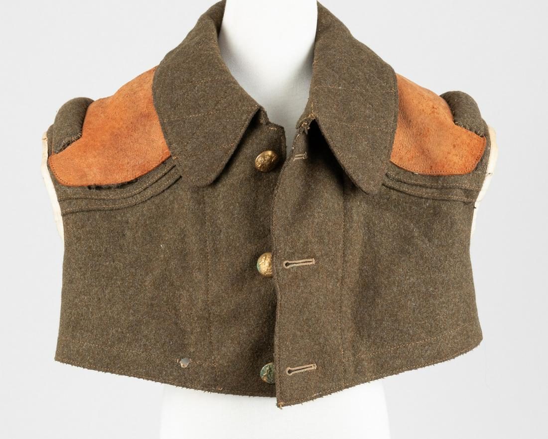 WWI BRITISH ARMY MACHINE GUNNERS VEST: Olive green wool machine gunners vest once belonging to an officer in the British Army during WWI, with leather cover and two wool shoulder pads, faint marking on inside '+ 8498', 14 x 21 inches. Thre