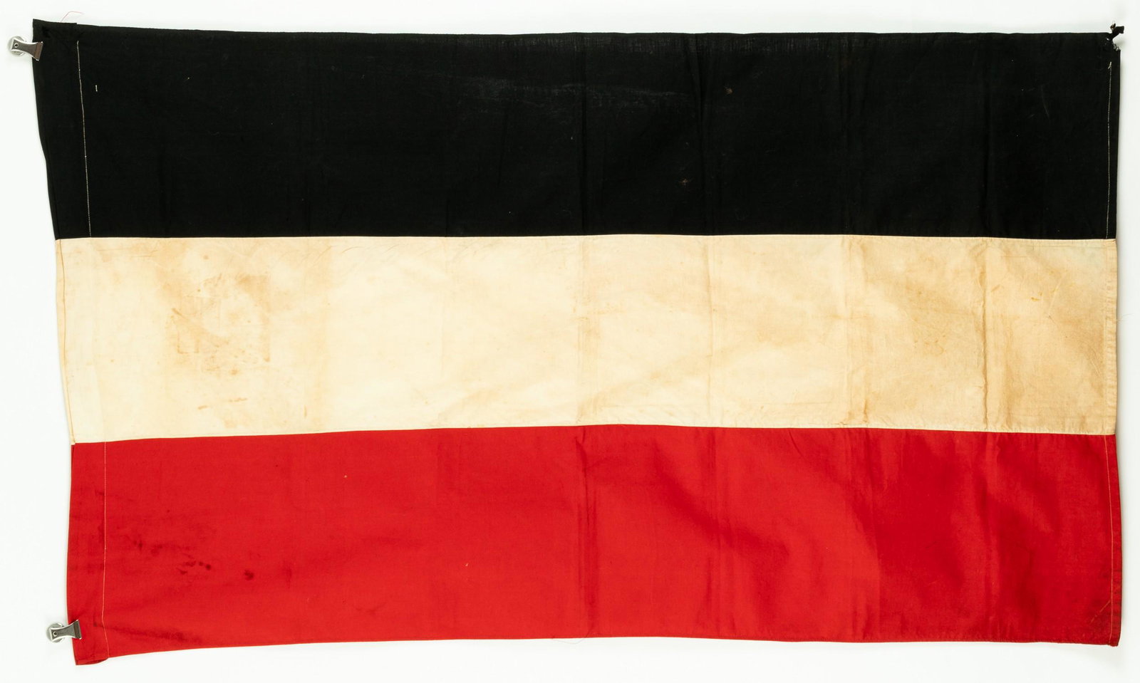 GERMAN FLAG NATIONAL COLORS: A black, white, and red tri-color flag of Germany, likely used between 1933 and 1935, shortly before the use of the German swastika flag, 54 x 31.75 inches. Each color is stitched together with white 