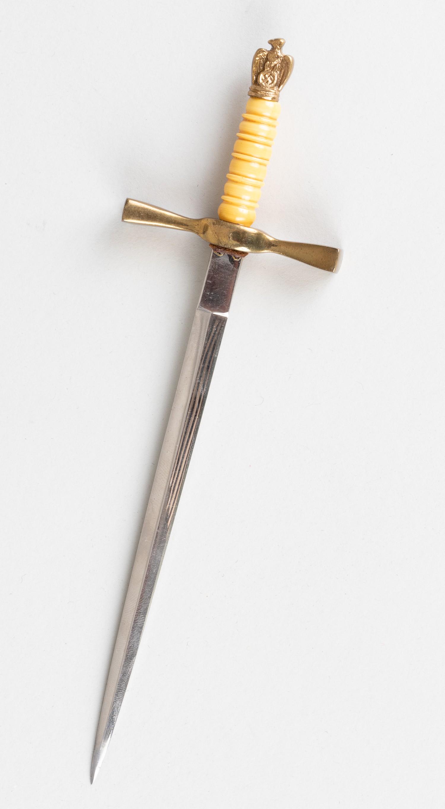 GERMAN KRIEGSMARINE DAGGER LETTER OPENER: Letter opener in the pattern of a German Kriegsmarine dagger. Brass colored eagle and swastika on pommel, tan plastic grip, brass colored cross guard. Included is a green storage case. Blade 5.25. Tot