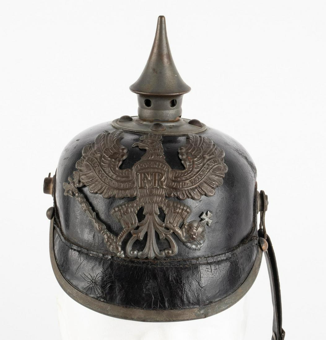 WWI PRUSSIAN M1915 PICKELHAUBE SPIKED HELMET: Prussian WW1 M1915 helmet. Comes with removable leather chin strap, and two metal cockades. Stamp on the neck guard of the helmet 'B. J. A. X'. Top of helmet shows wear. The chin strap is slightly spl