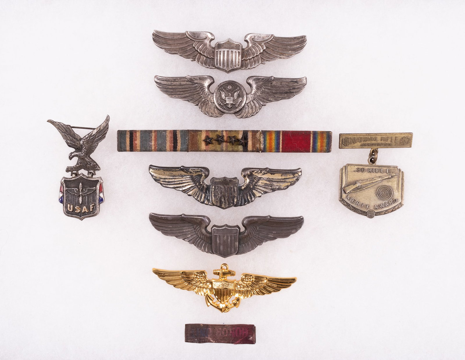 5 UNITED STATES MILITARY WINGS: Five United States Military wings. Two wings are air force, two wings are army, and one wing is navy. The two air force wings are both silver. One wing is for a pilot and displays a shield in the cent