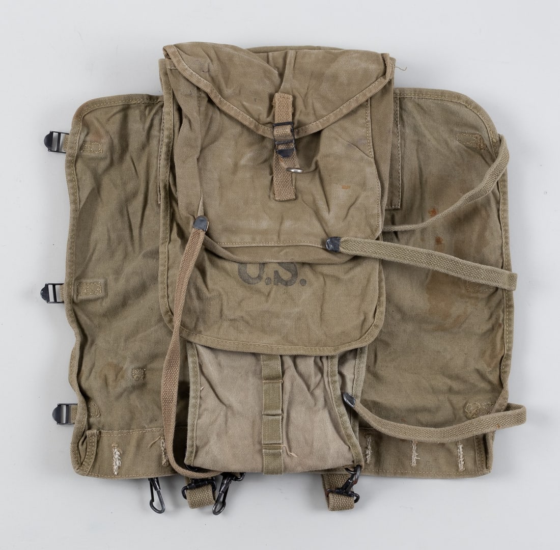 WWII U.S. BACKPACK: U.S. model M1928 haversack. The M1928 was the standard issue backpack for U.S. soldiers in WWII. The backpack was made to fold around the soldiers kit. Green canvas backpack with one pouch on the back