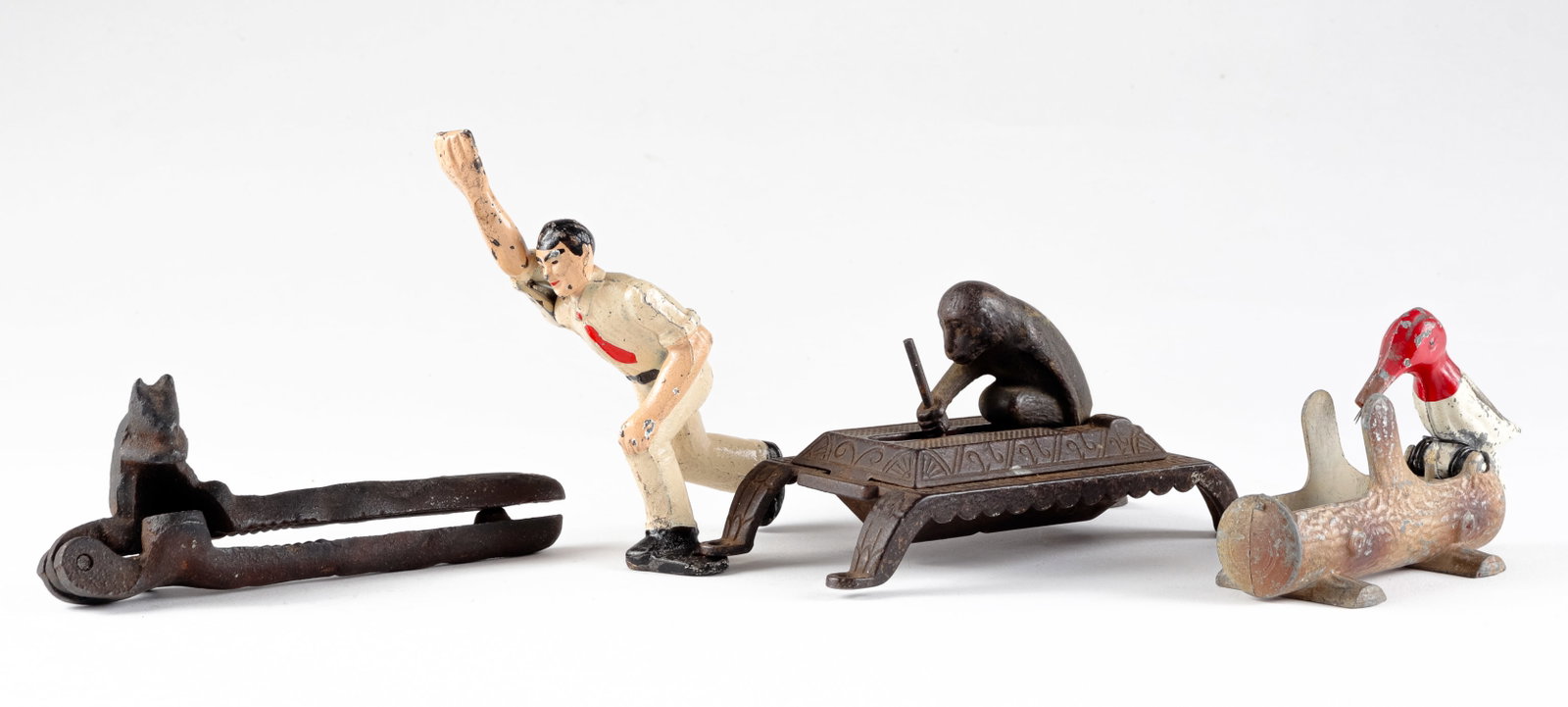 FOUR ANTIQUE CAST IRON MECHANICAL TOYS: Four antique mechanical cast iron toys, includes a monkey tooth pick tray, a woodpecker on a log, a nutcracker, and a bowler with moveable arm.