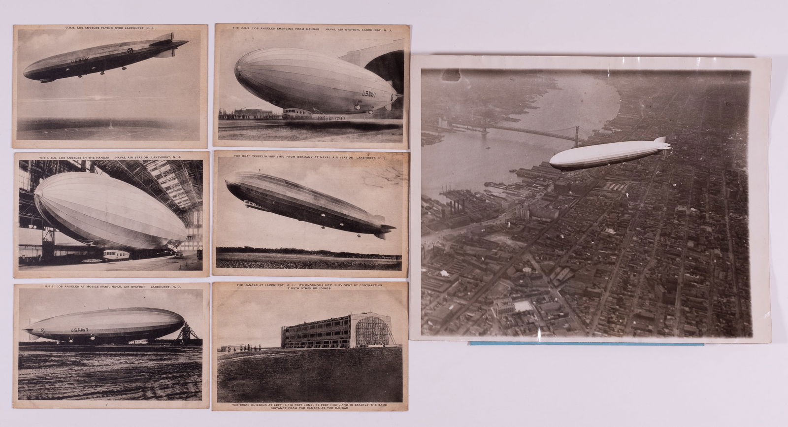 7 ZEPPELIN POSTCARDS + PHOTOGRAPH: Series of six American Zeppelin postcards at Lakehurst, NJ. Includes one card showing the Graf Zeppelin, some soiling of the cards. WITH: One original b/w press photograph of the Graf Zeppelin over Ne