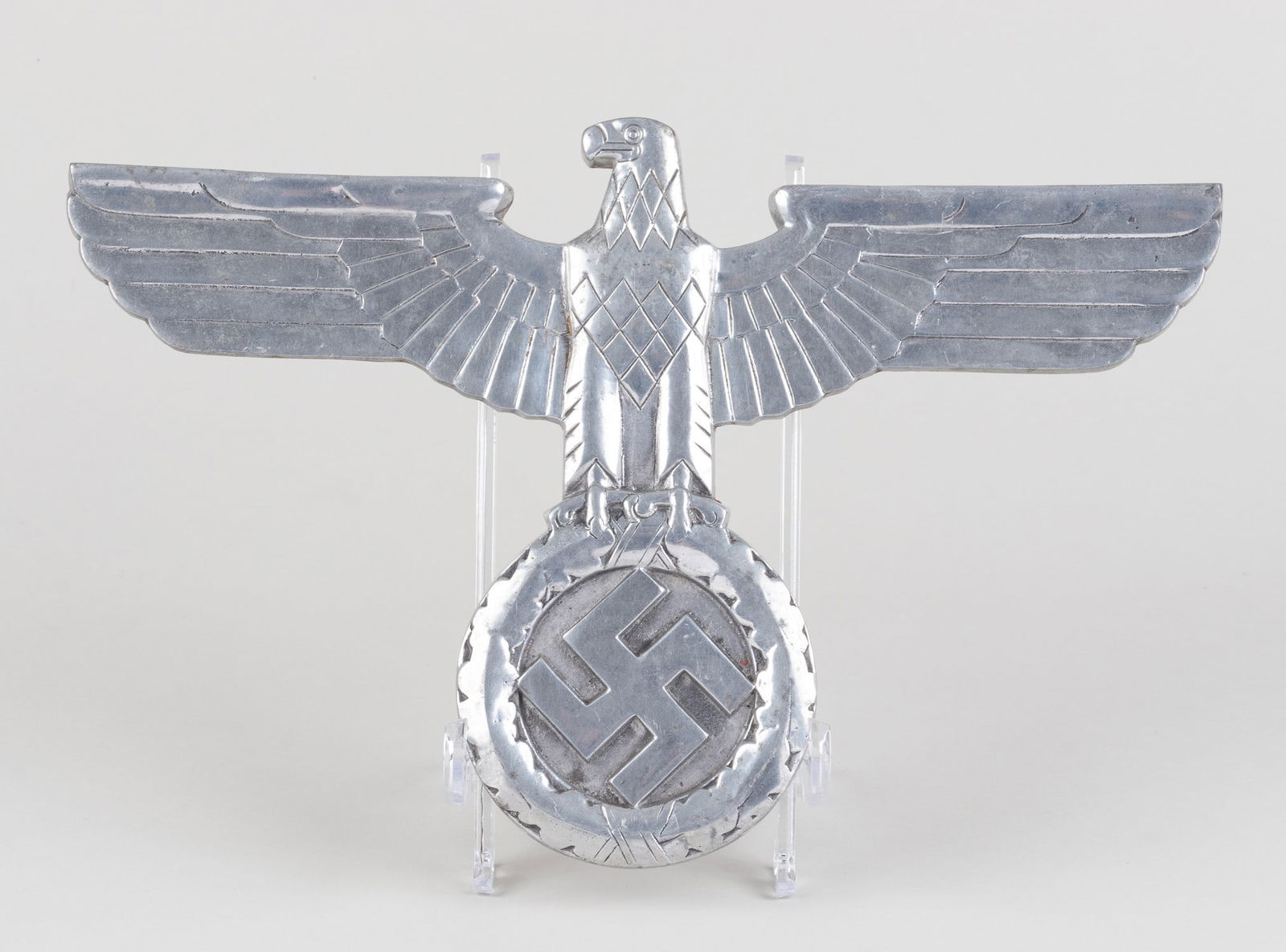 POST-WAR GERMAN RAILWAY EAGLE: Post-war casting of a Nazi Railroad eagle. The eagle clutches an oak leaf wreath with a mobile swastika and has a shiny chromed finish, wingspan is 15 inches and approx. 10 inches tall.