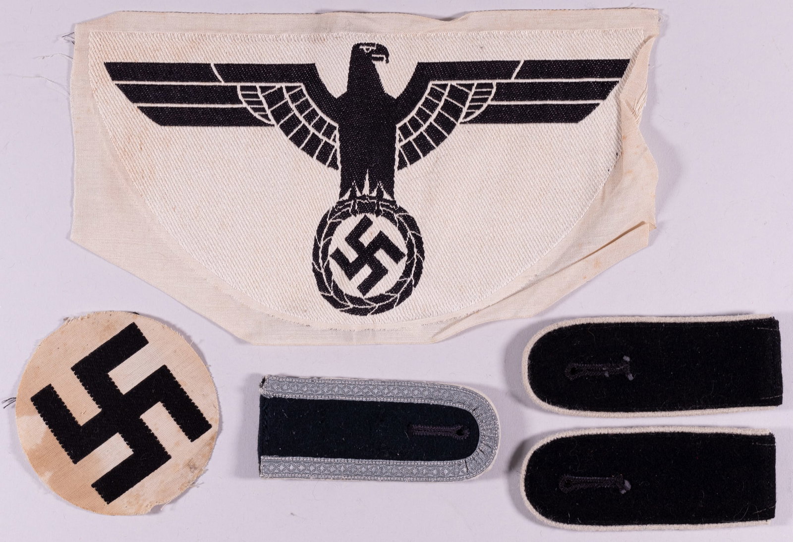 WWII GERMAN SPORT SHIRT EAGLE: Five German embroidered insignias and shoulder boards, includes a large sport shirt Wehrmacht eagle, a pair of infantry shoulder boards, a single shoulder board, and an embroidered swastika cut from a