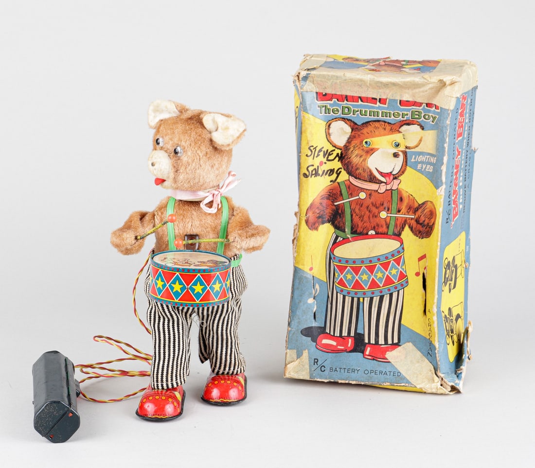 CRAGSTAN BARNEY BEAR DRUMMER BOY JAPAN: Barney Bear the Drummer Boy with remote control. Cragstan Toy, Japan, with original box, approx. 11 inches tall. Box worn and damaged. Battery operated, partial tin, with flip up snare drum. Not teste